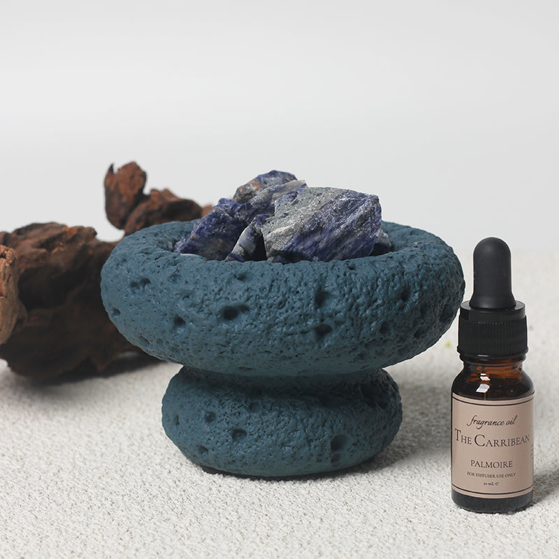 Blue Moon Diffuser displayed with essential oils, with nature in the background