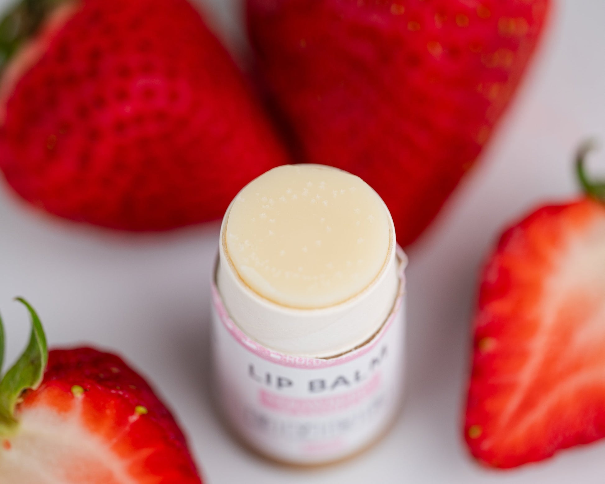 Open Lip Balm showcasing texture with strawberries in the background