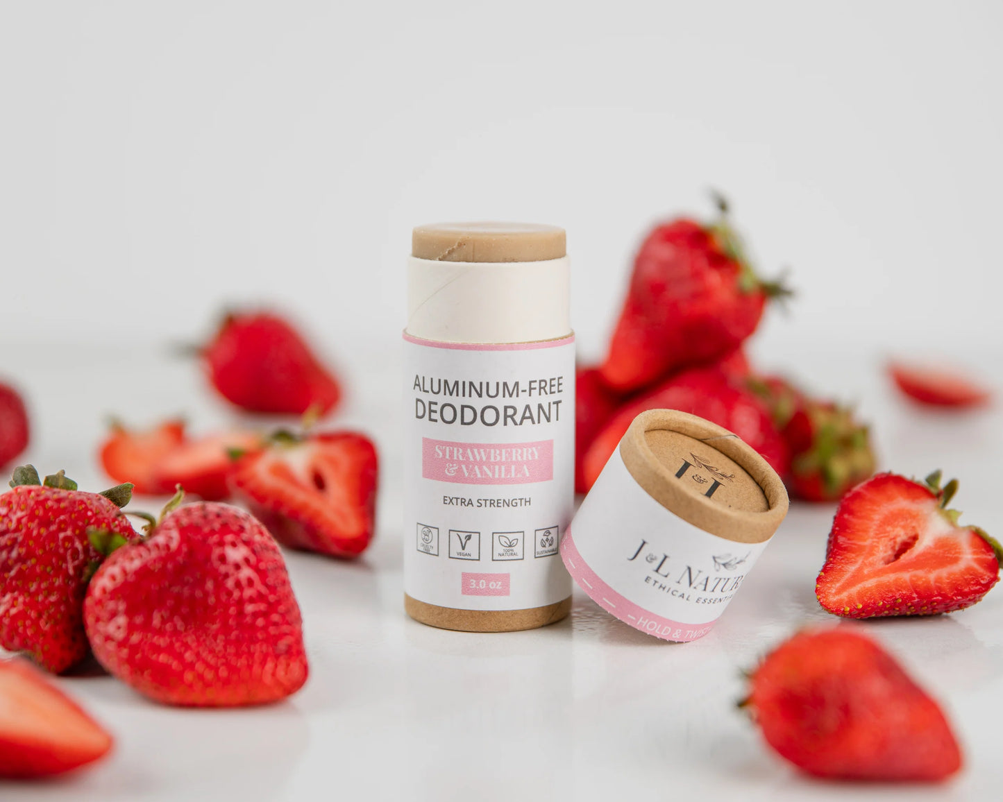 Close-up of the Strawberry & Vanilla Deodorant stick with fresh strawberries in the background